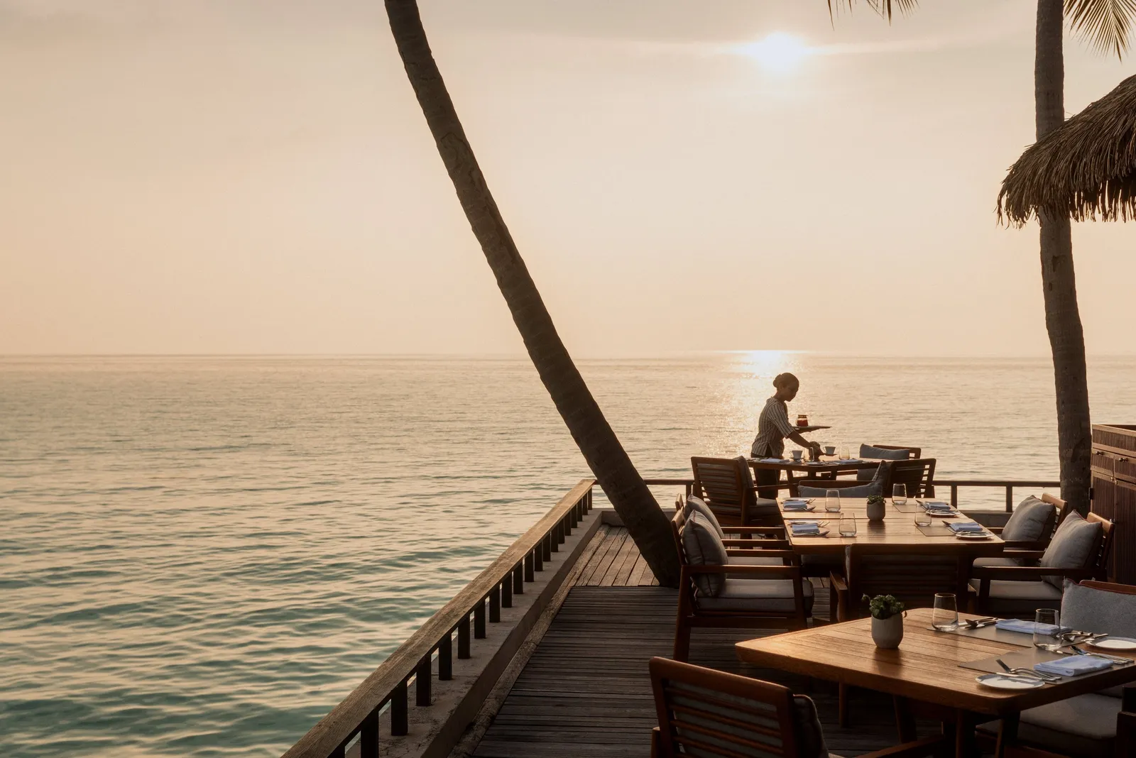 Tables on Reethi’s over-water veranda, the sun low over the sea