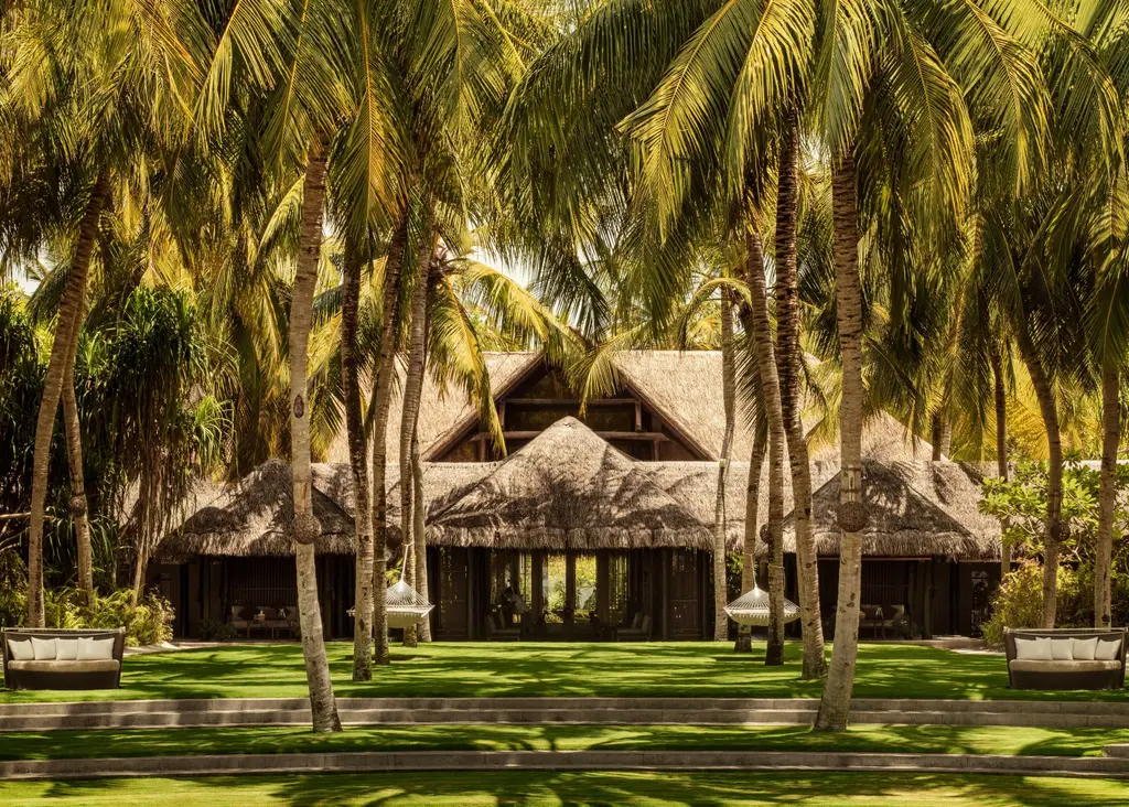 A thatched spa pavilion among the palms and the lawn