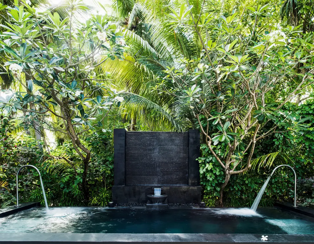 The spa’s vitality pool among the plants, water falling from the wall