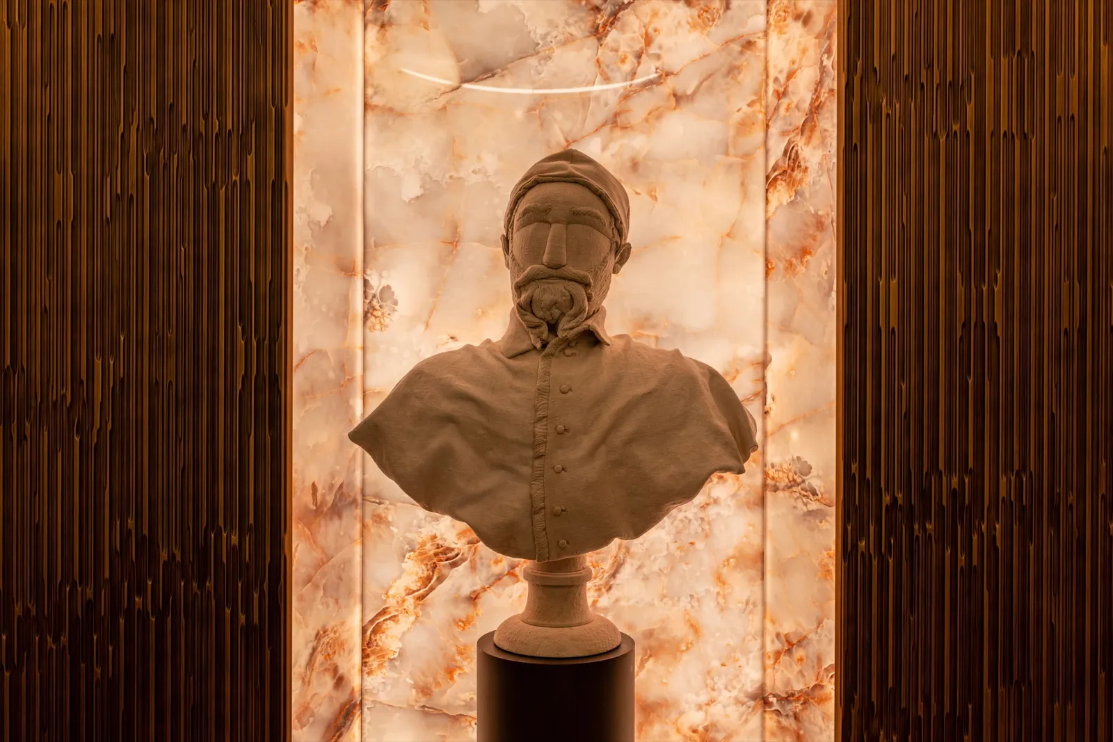 The bust of Cardinal Federico Borromeo against a backlit onyx wall at Residenza del Cardinale