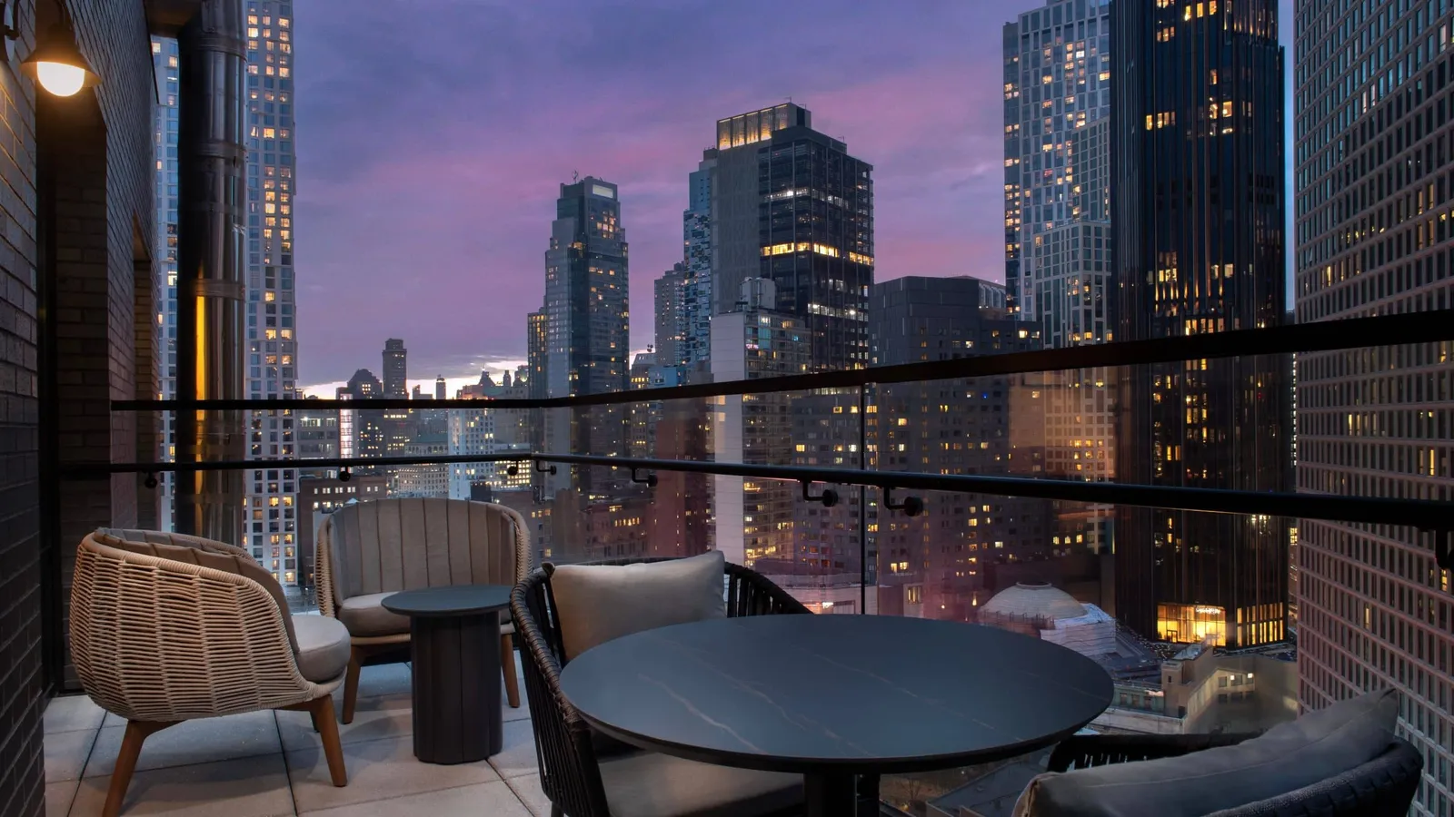 Il balcone del Livingston al crepuscolo, con tavolo, sedie e lo skyline di Brooklyn