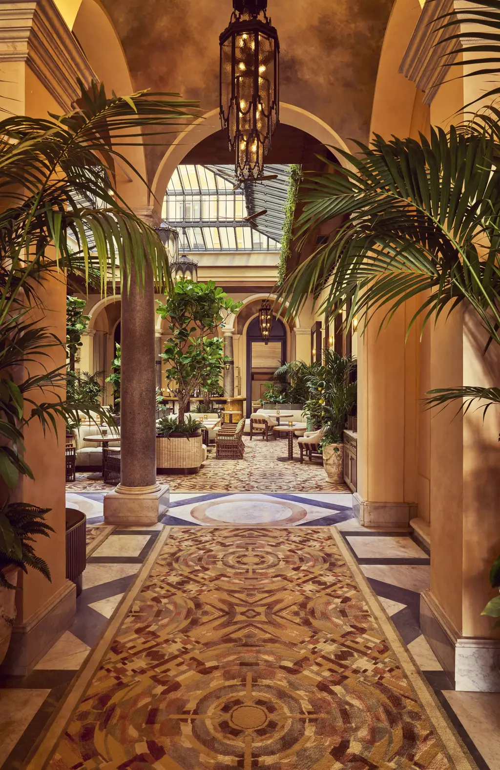 The entrance corridor under palms, leading to the glass-roofed atrium