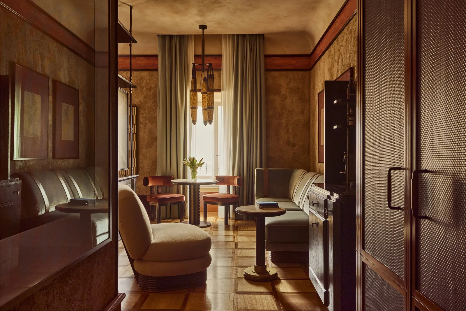 A Junior Suite with 2 armchairs, a small table and the window