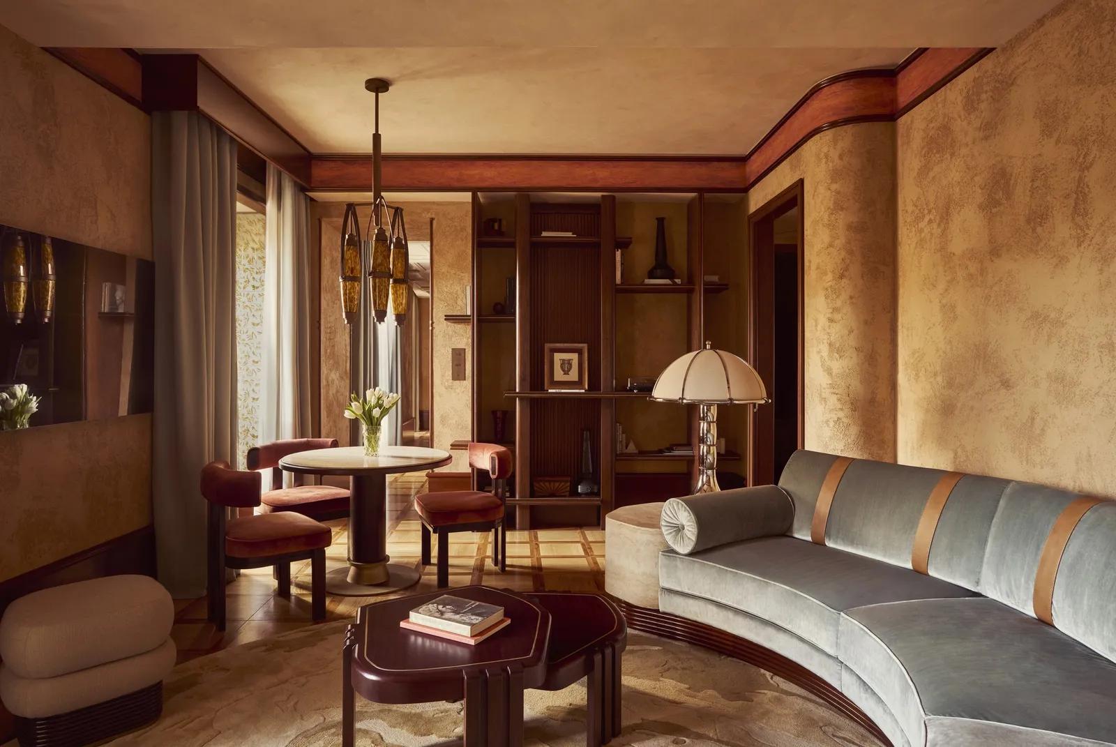 The Suite’s sitting room with a curved sofa and the bedroom through the door