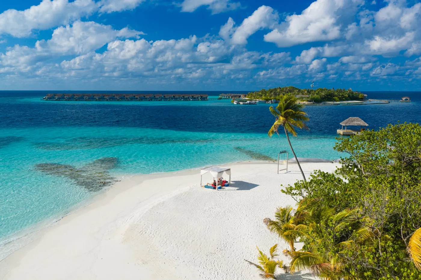 Lonubo’s sandy spit from above, with a white gazebo, palms and the turquoise lagoon, and Maafushivaru on the horizon.