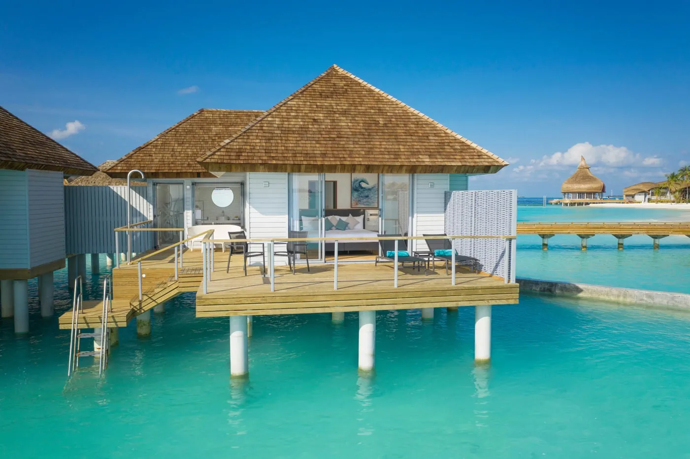 An Over Water Villa on stilts above the lagoon, with its deck, loungers and the ladder down into the water.