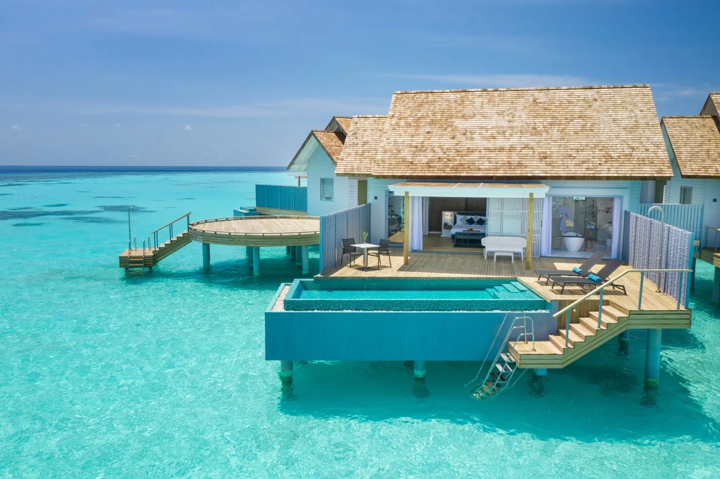 An Over Water Villa with Private Pool from above: the pool at the edge of the deck, the steps into the water and the turquoise lagoon all round.