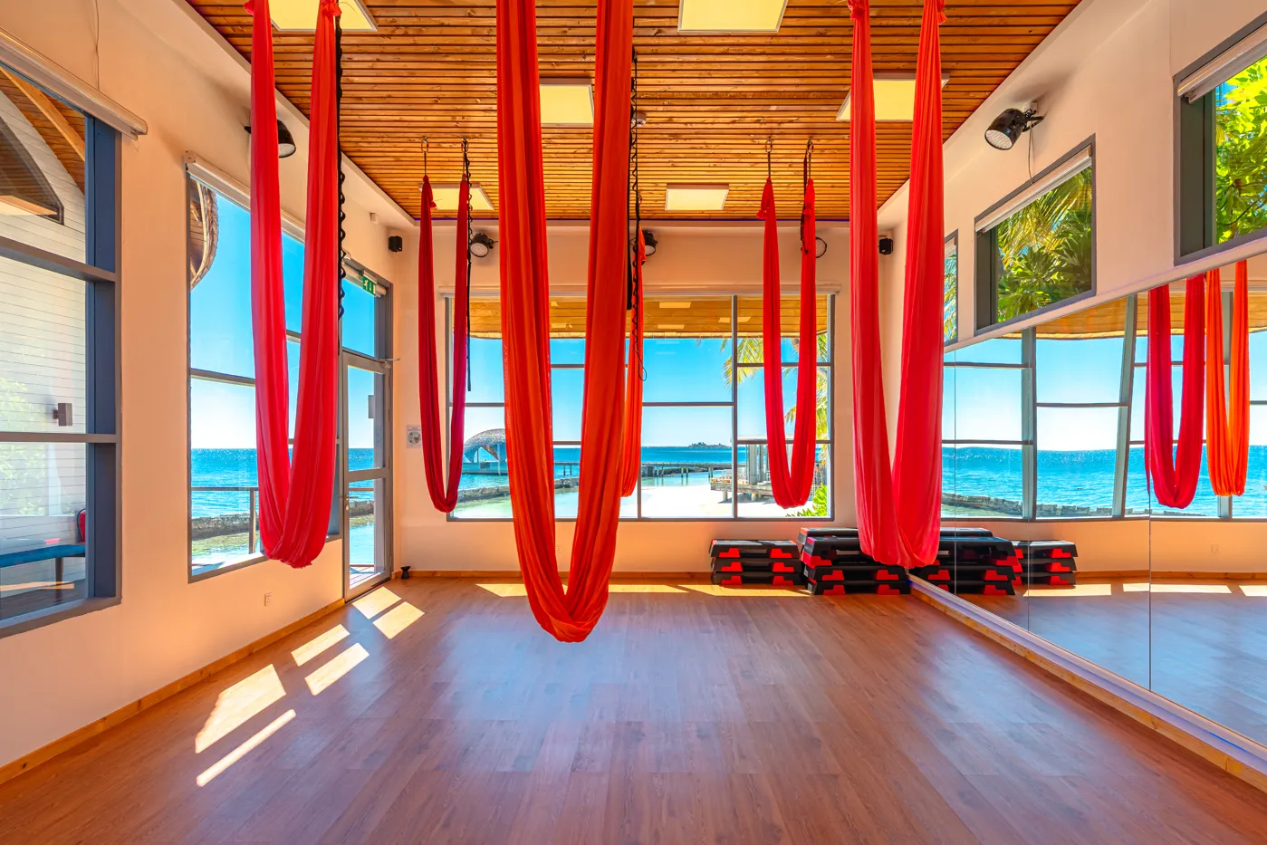 The spa’s aerial yoga room, red hammocks hanging from the timber ceiling and windows on the sea.