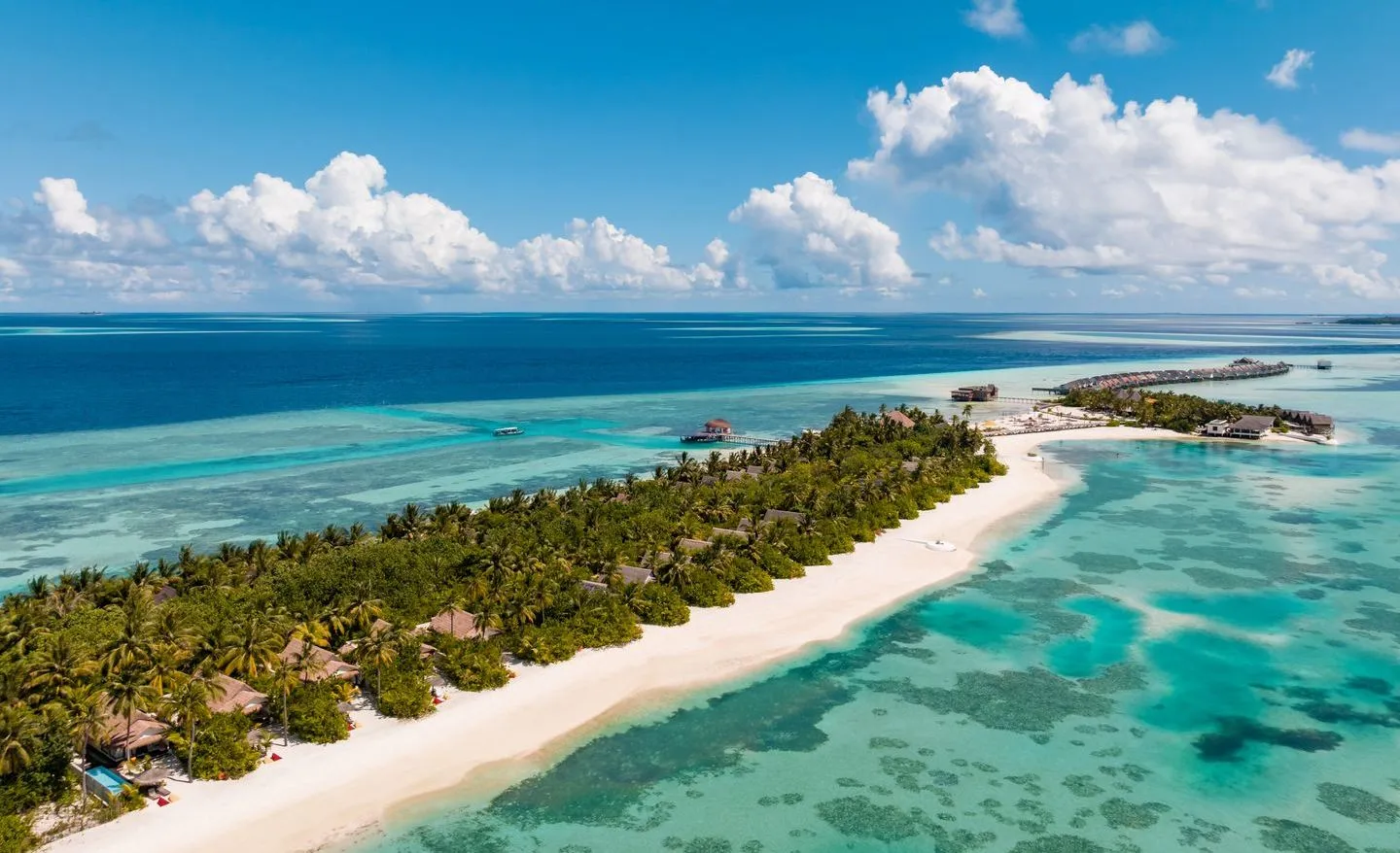 Maadhoo from above: the palm-covered island with its tongue of white sand and the water villas beyond.