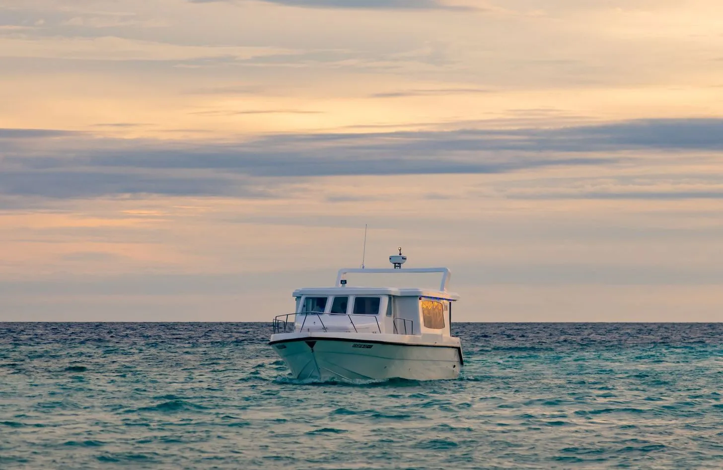 The resort’s speedboat on the open sea at sunset, under a pink and grey sky.