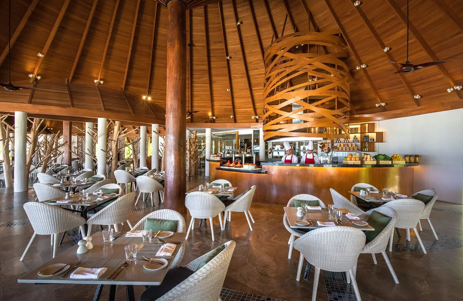 THE PALMS under its timber roof, white woven chairs and chefs at the open kitchen.
