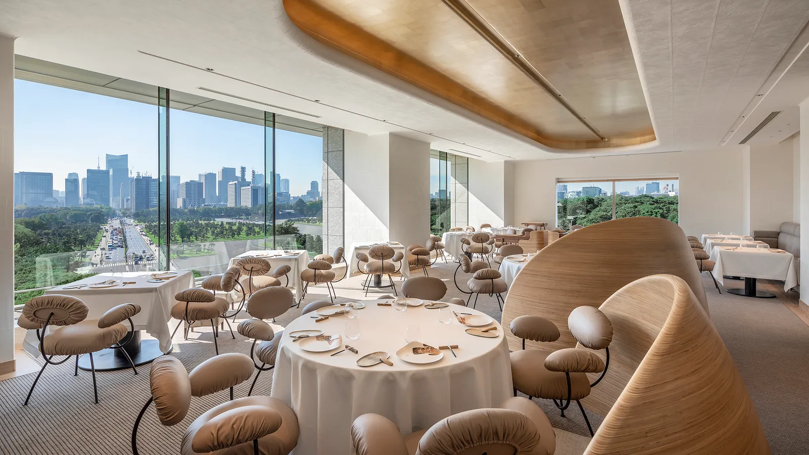 Esterre’s dining room by day: laid round tables, curved wooden chairs and the windows over the moat and the city.