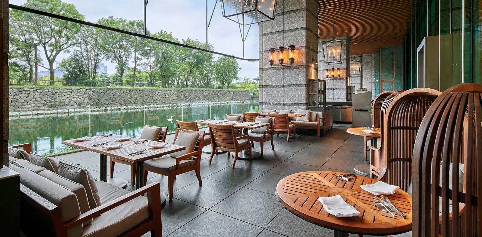 Grand Kitchen’s terrace on the moat, its tables laid facing the stone walls and the trees.
