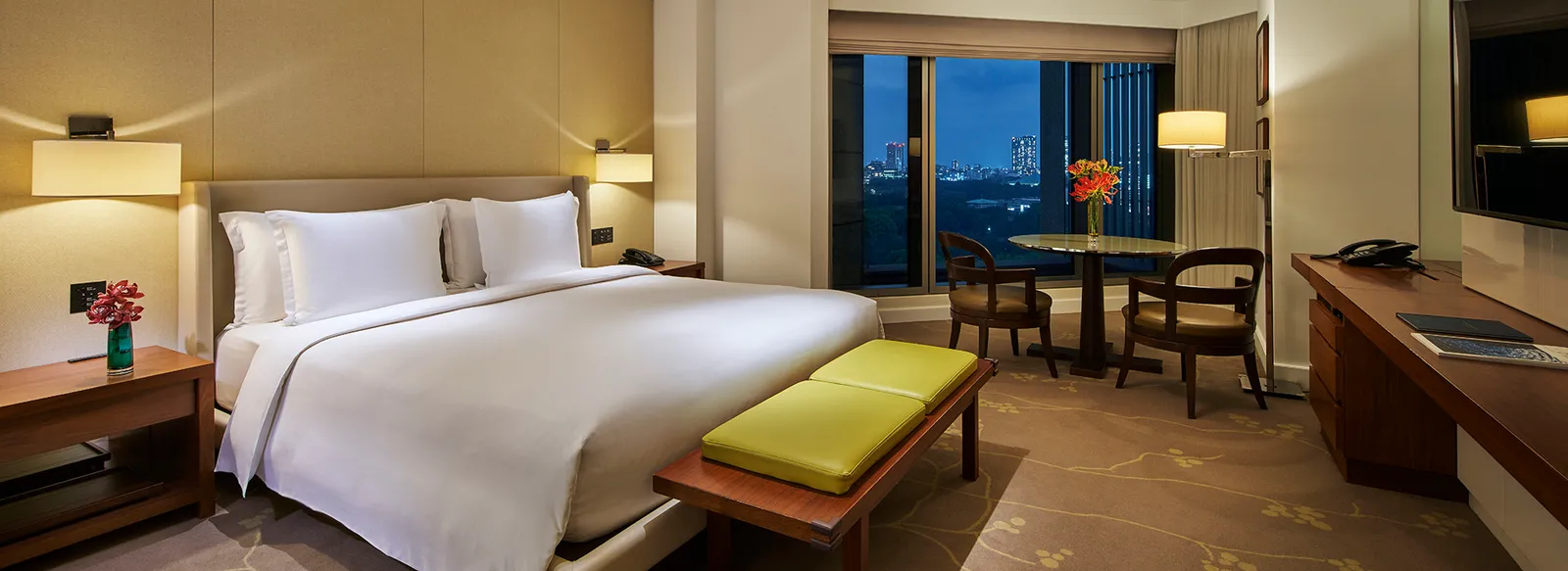 A king room in the evening, with the lights of the towers beyond the window.