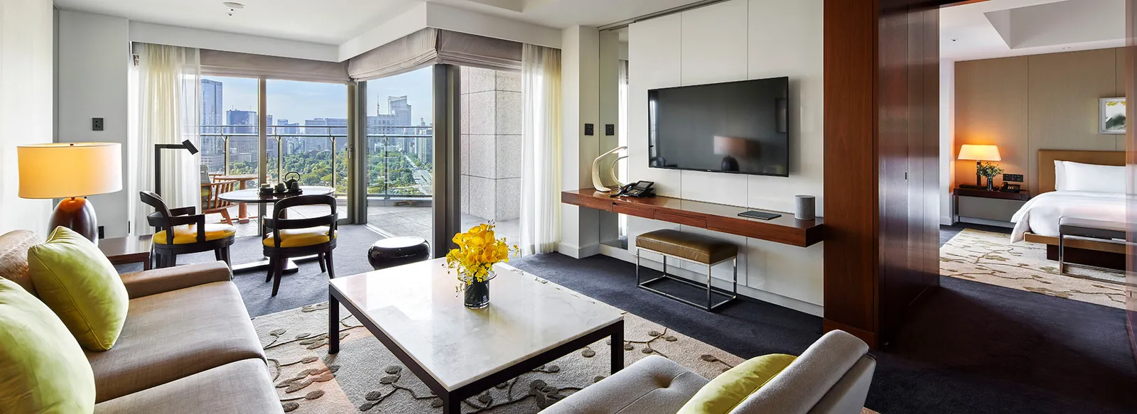 The Executive Suite’s living room: the sofa with green cushions, a table with flowers and the bedroom beyond the door.