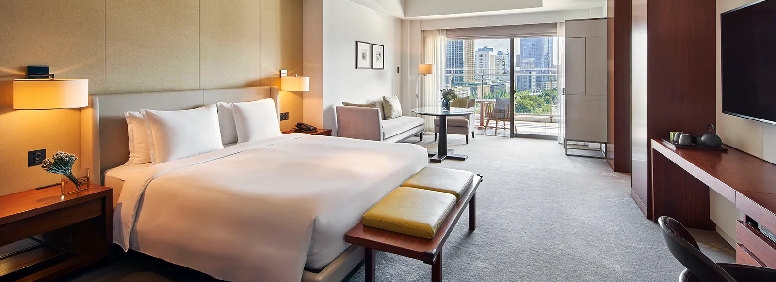 A Grand Deluxe with a king bed and green bench, the window seat and the view of the gardens.