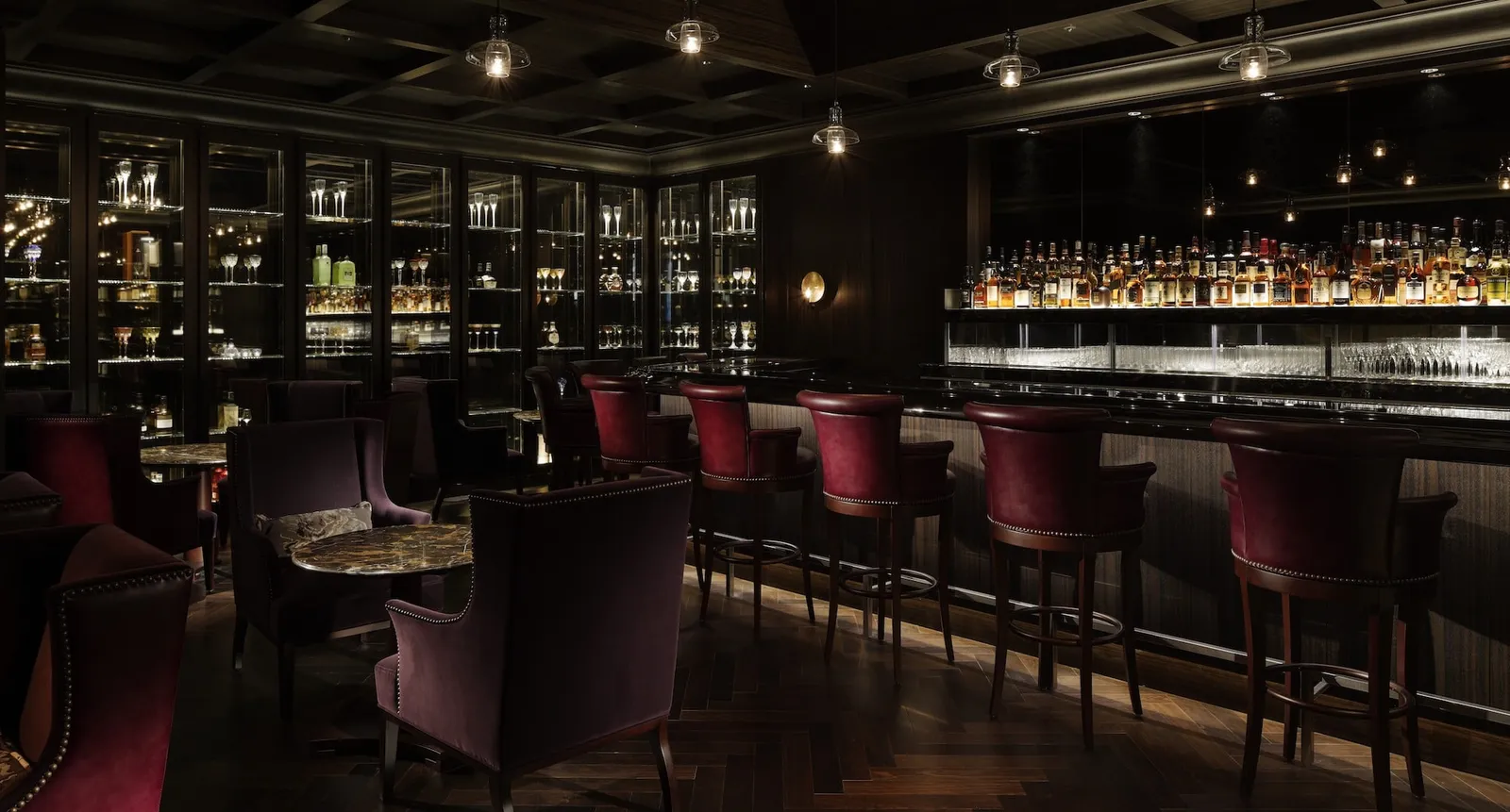 Royal Bar: the dark-wood counter, red velvet stools and the lit bottles on the shelves.