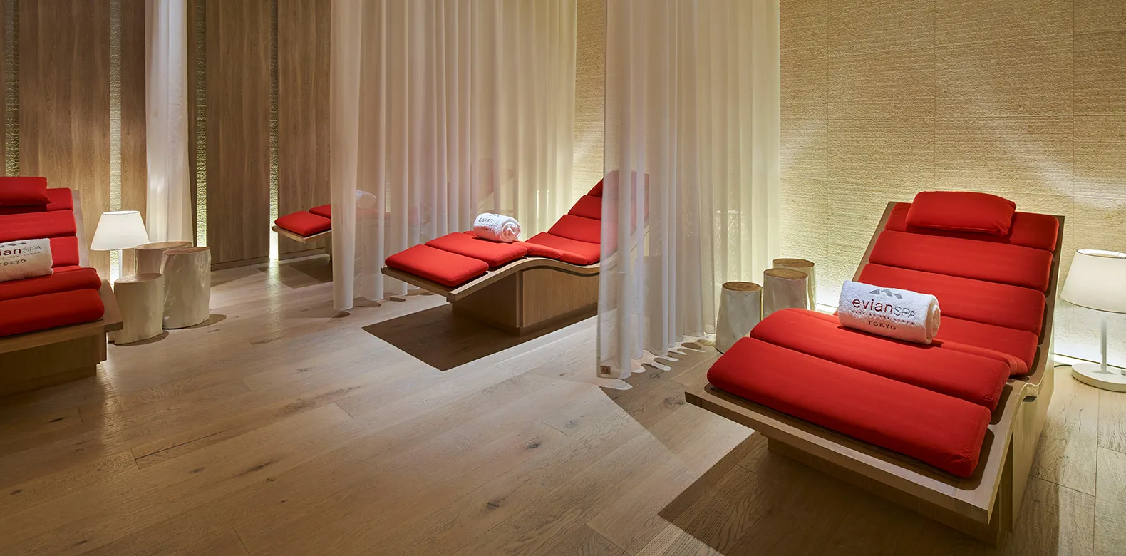The evian SPA relaxation lounge: red loungers between white curtains on a wooden floor.