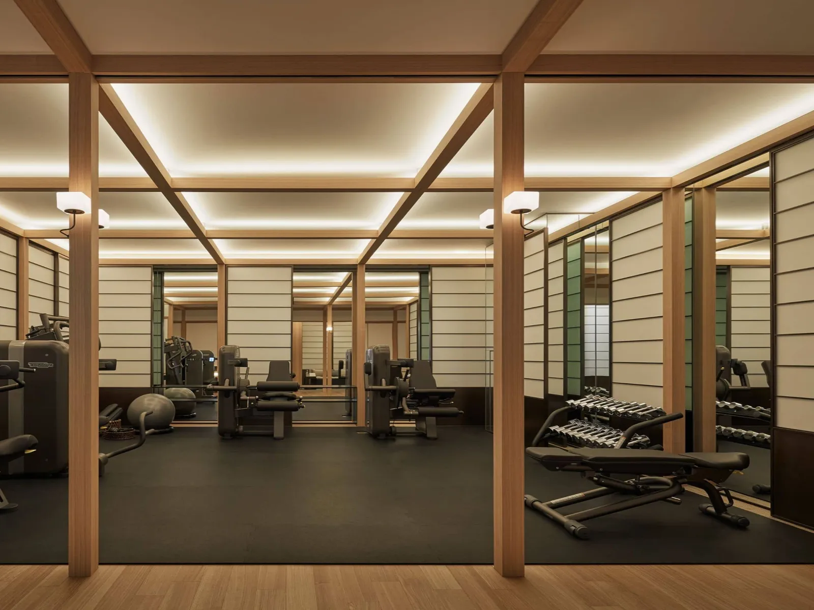 The gym between timber posts and paper screens, with the weights and machines.