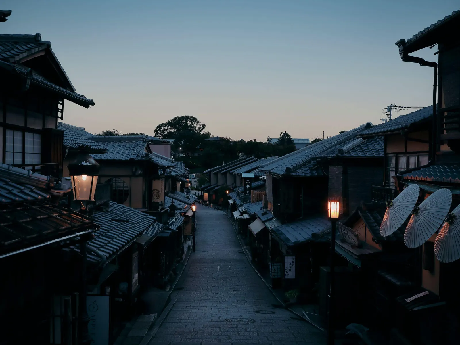 Ninenzaka at dawn, empty: the stone steps between the wooden townhouses, the lanterns still lit.