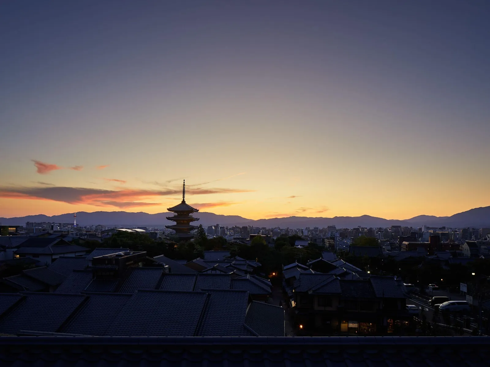 Yasaka Pagoda in silhouette at dusk, above Kyoto’s rooftops and the mountains to the west.