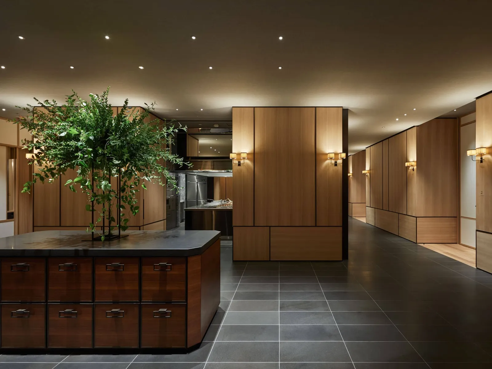 The foyer of the Komorebi ballroom, with a dark timber counter, a potted tree and timber walls.