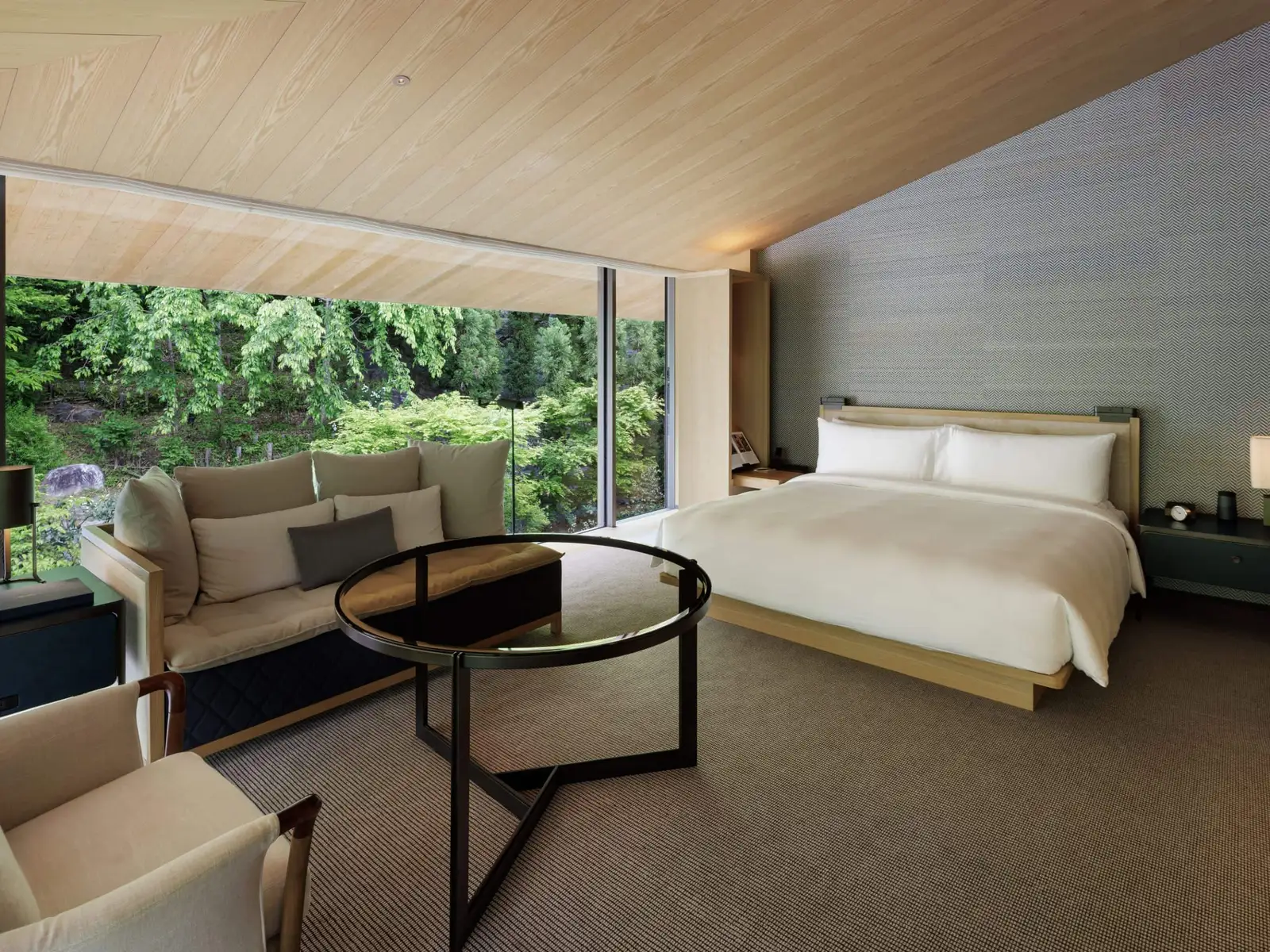 The garden-view king room: the bed, the glass table and the window onto trees and stones.
