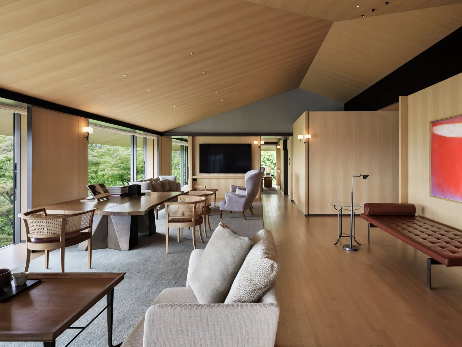 The Pagoda House living room under its sloping timber ceiling: the dining table, the sofa and the garden.