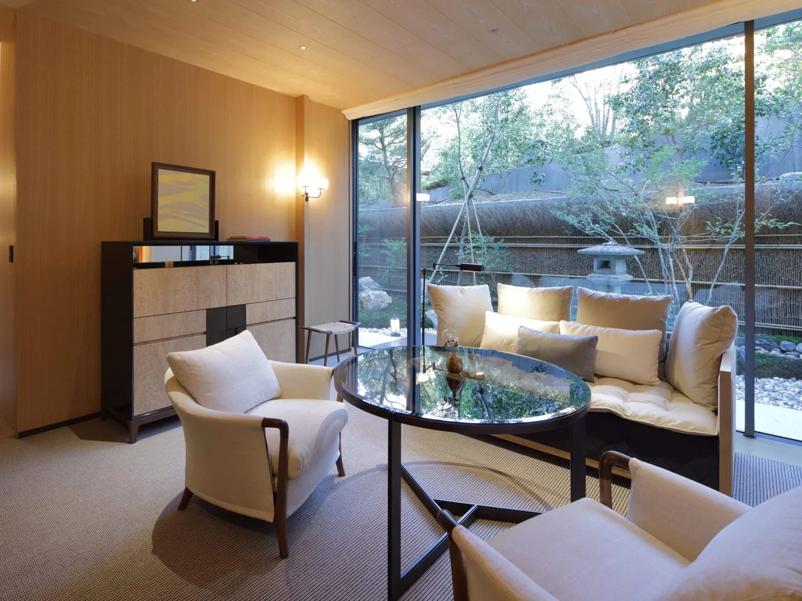 The Park Suite’s living room: armchairs, a glass table and the window onto a garden with a lantern.