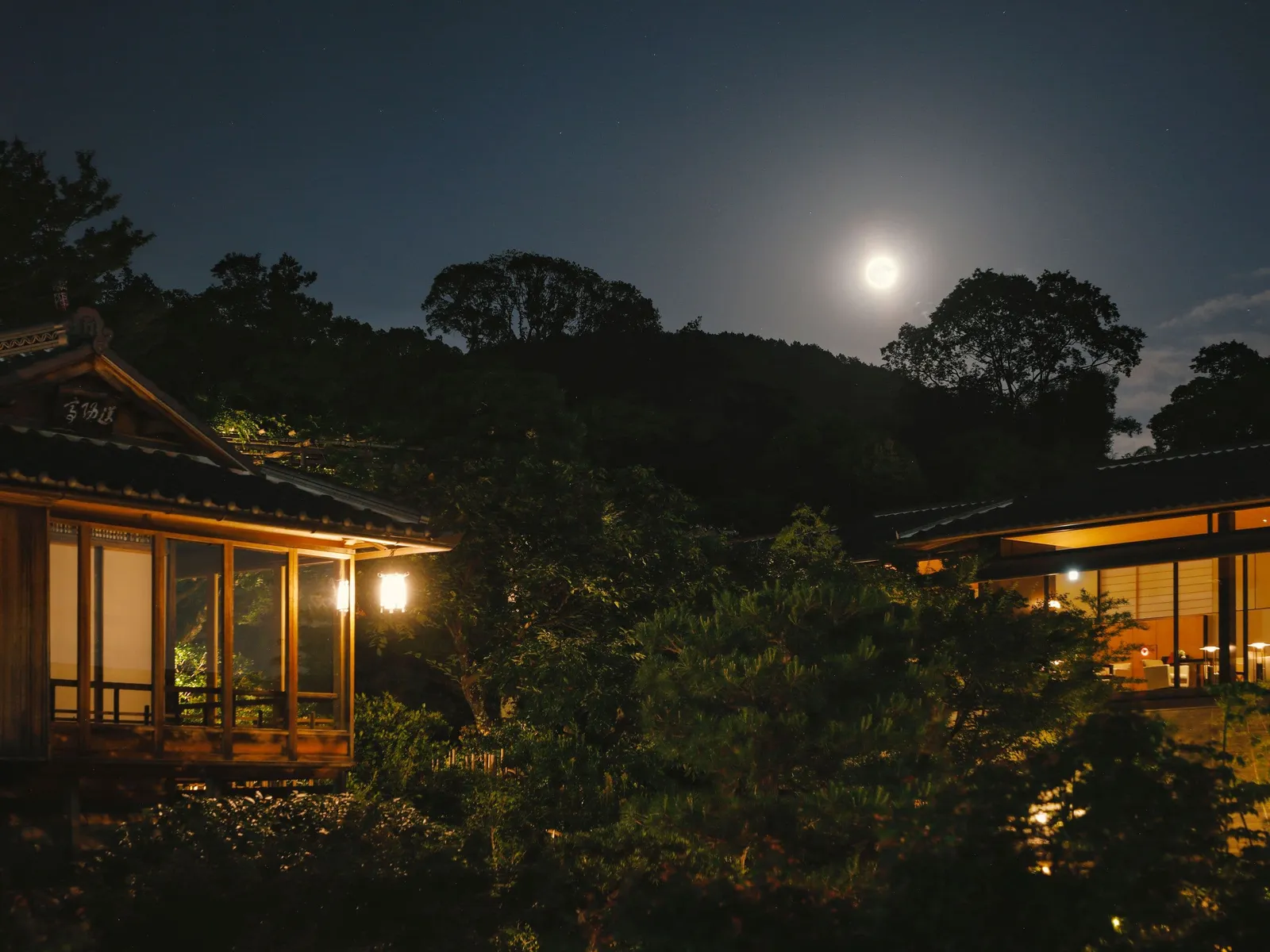 A full moon over the Kyoyamato garden, with a lit teahouse among the trees.