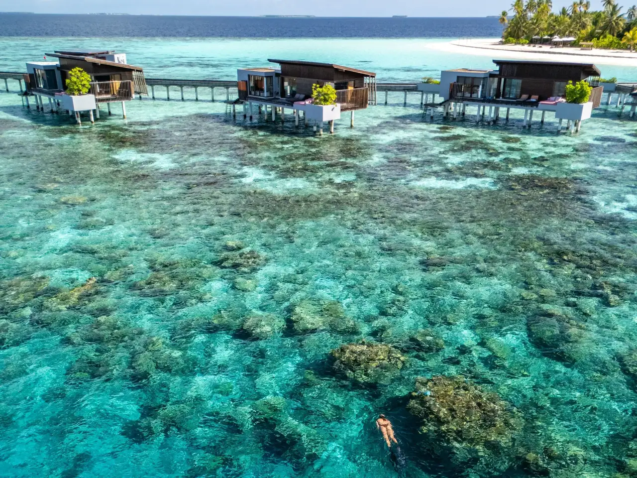Overwater villas above the lagoon and coral