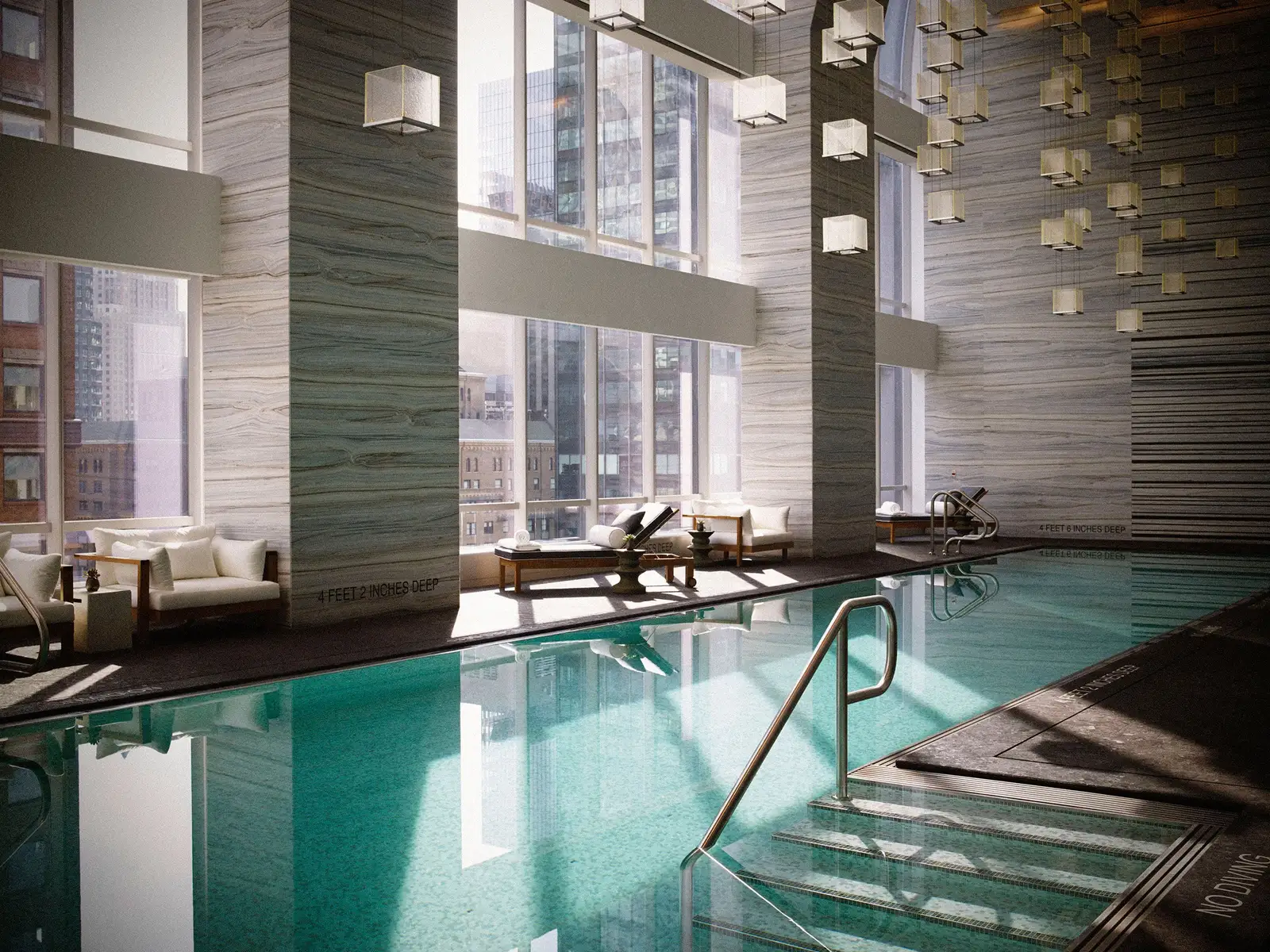 Indoor pool with tall windows, loungers and stainless-steel handrails