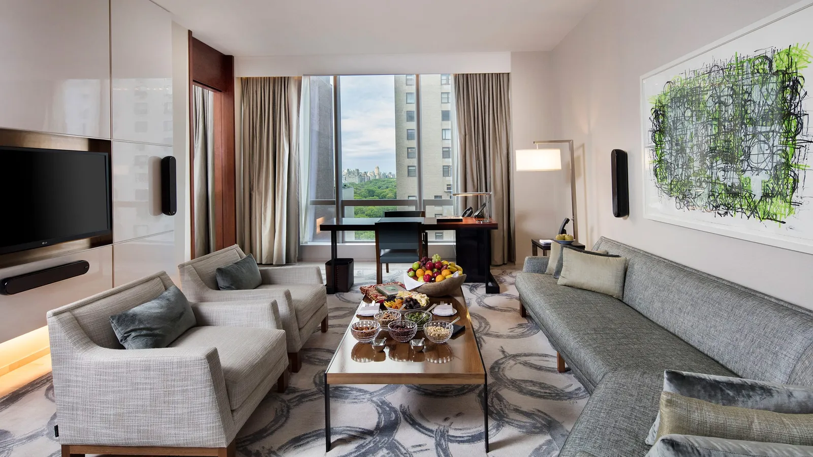 Living room with grey sofa, a laid table and a glimpse of the park