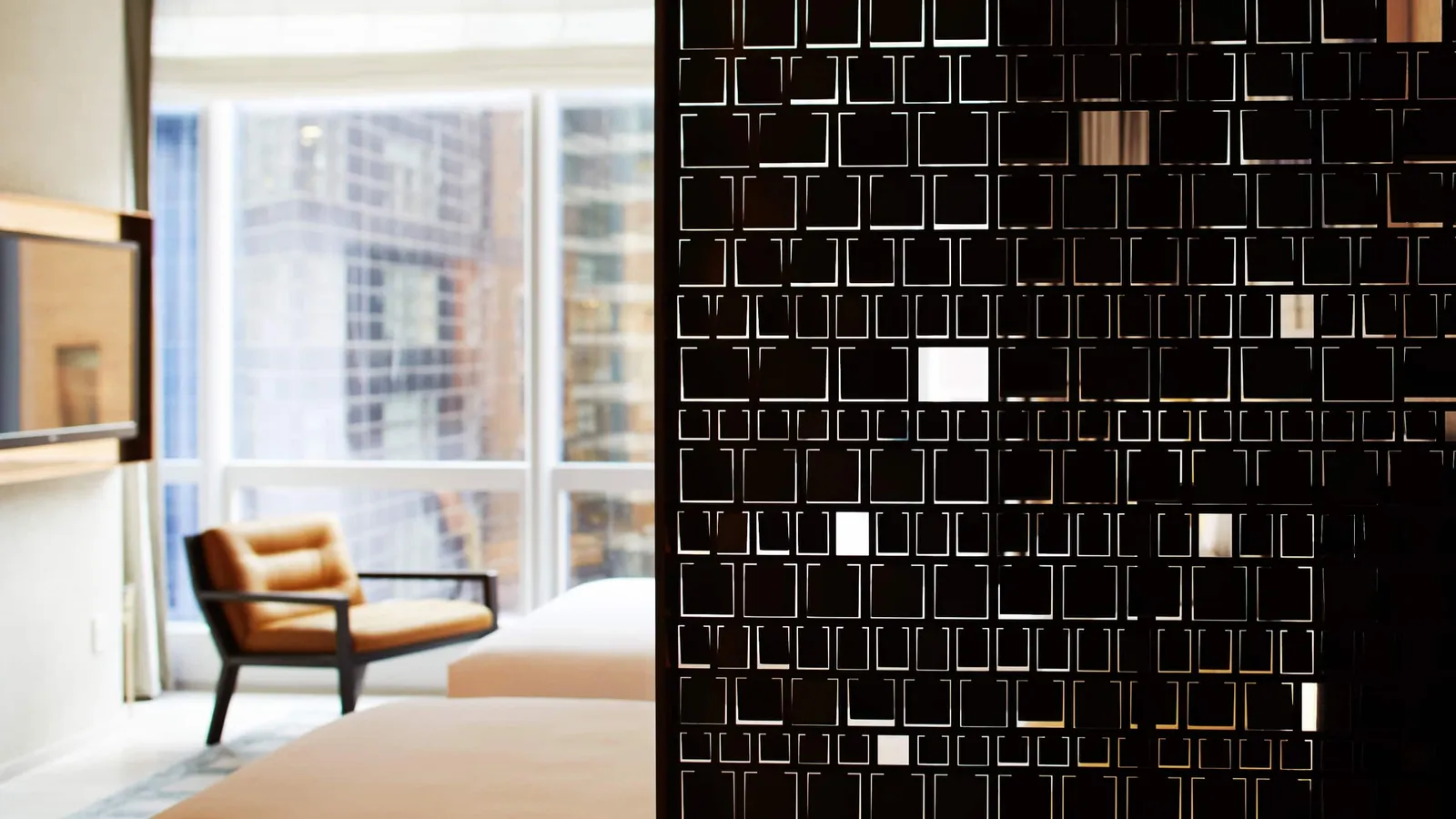2 beds behind a perforated screen and an armchair beside the windows