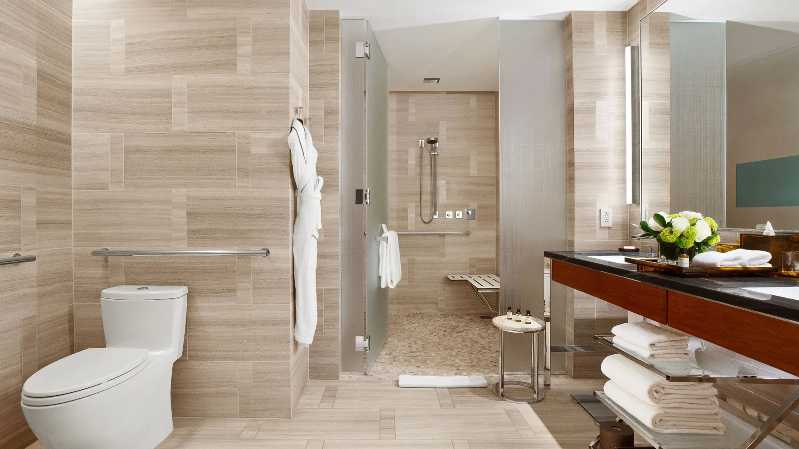 Level-access shower with seat and grab rails beside the vanity
