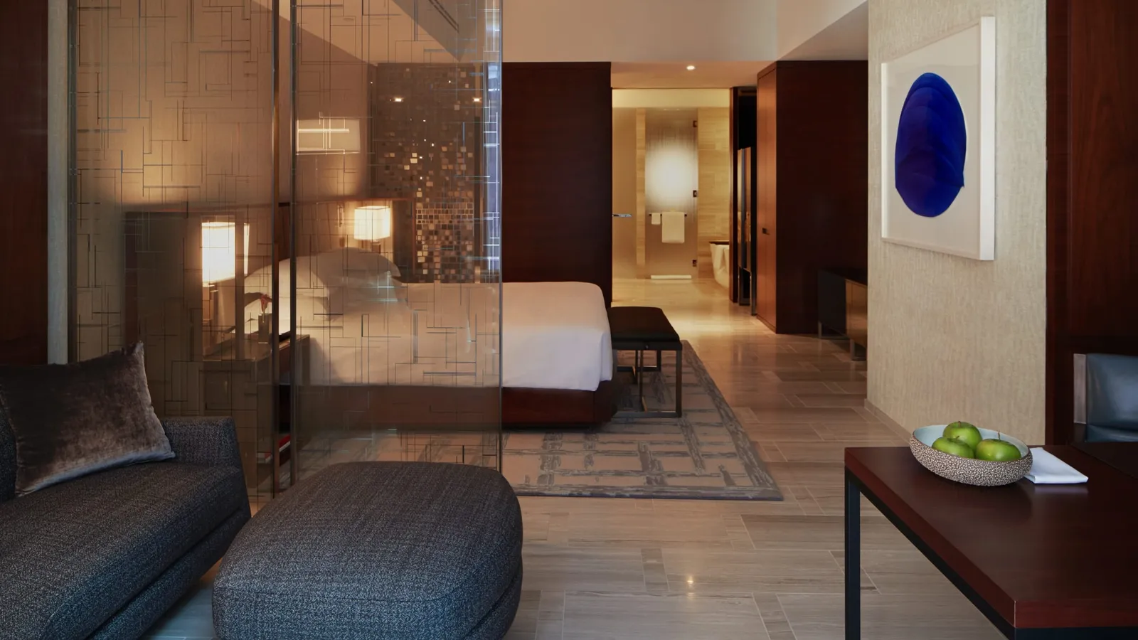 King bed behind decorative panels with a passage towards the bathroom
