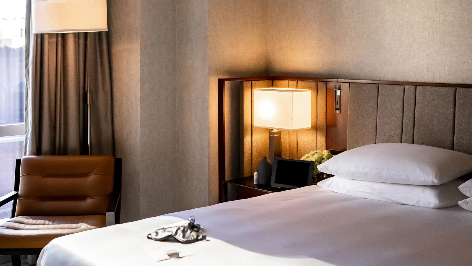 Bed with a sleep mask, bedside lamp and window-side armchair