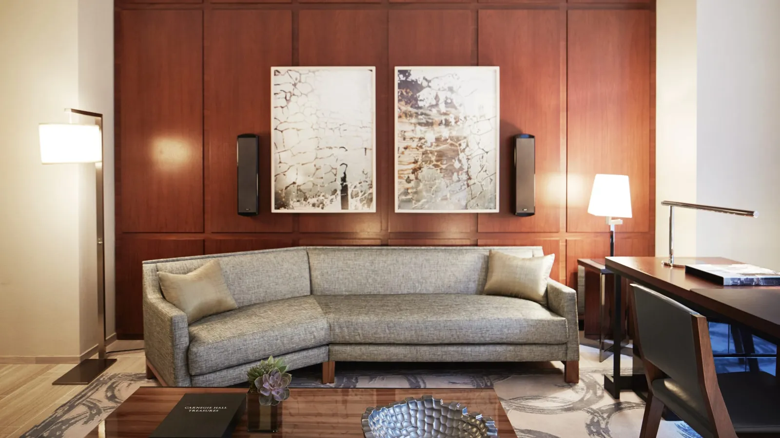 Sofa against a wood-panelled wall with artwork and a desk