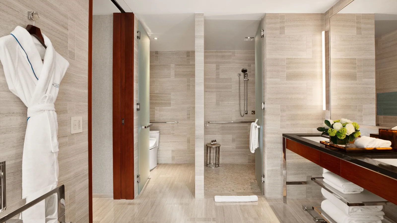 Level-access shower with grab rails in a pale stone bathroom