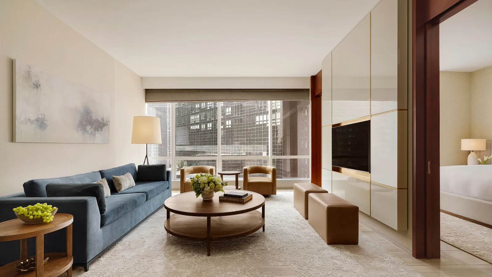 Living room with blue sofa, round tables and an opening into the bedroom