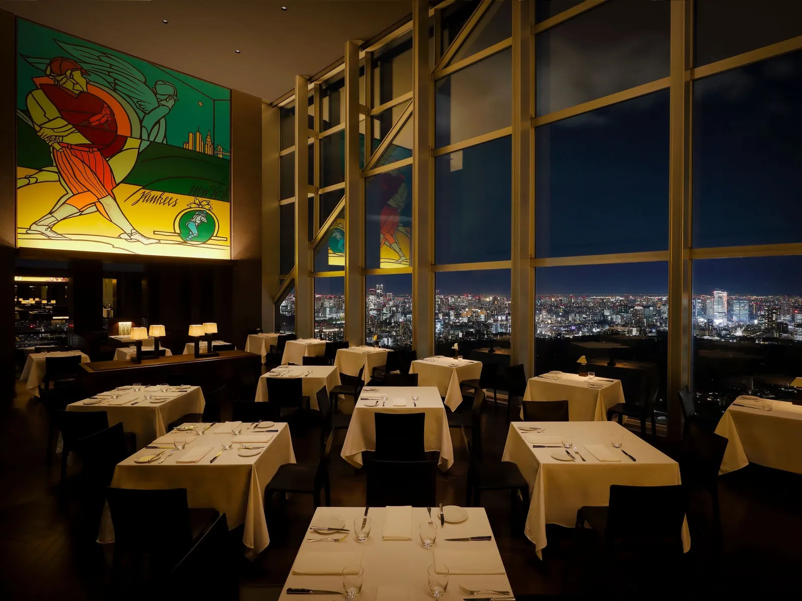 New York Grill at night: the laid tables, the tall windows over the city lights and a colourful Valerio Adami mural.