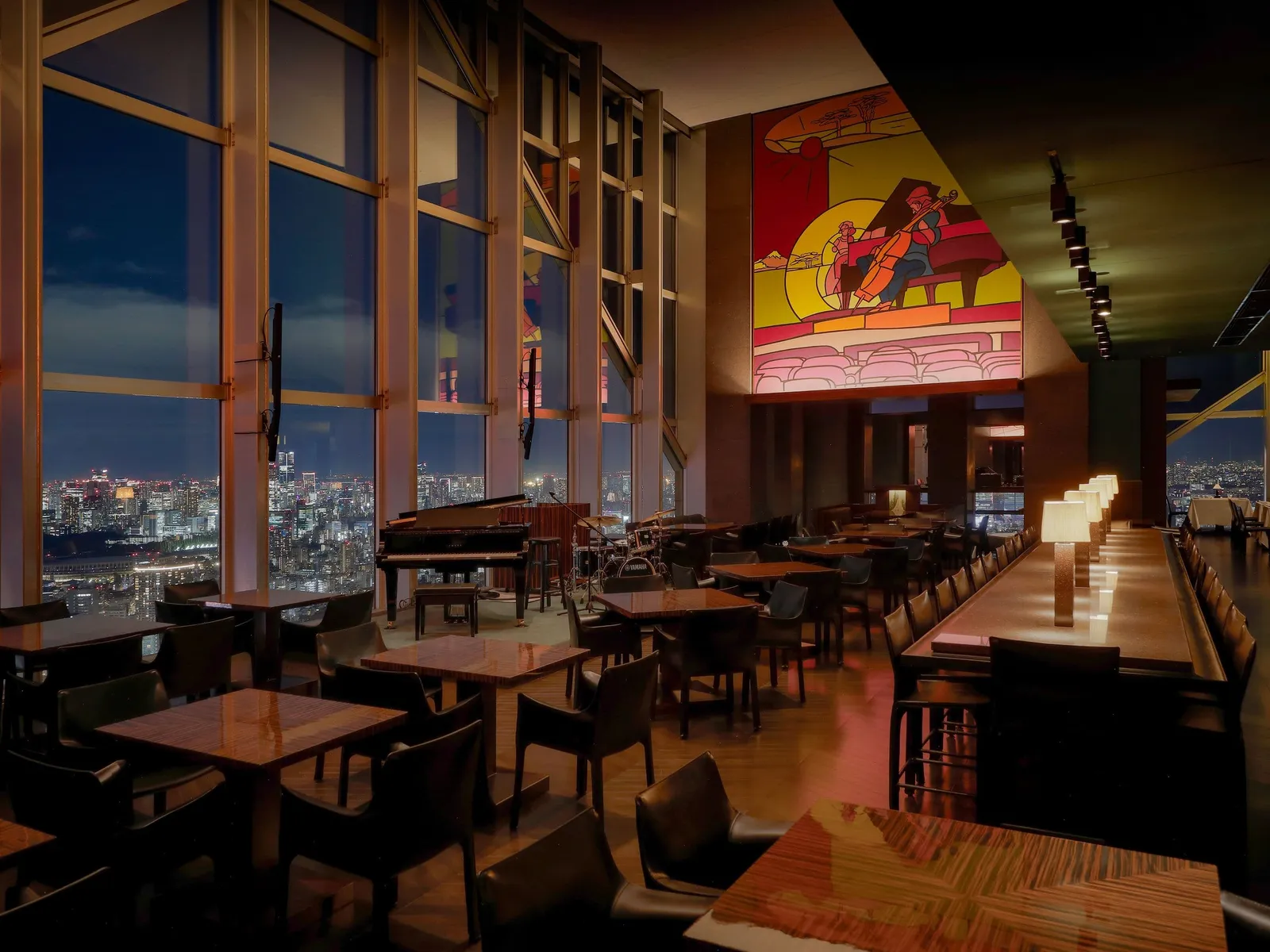 New York Bar at night, with its grand piano, tables by the windows over the city and the Valerio Adami mural.