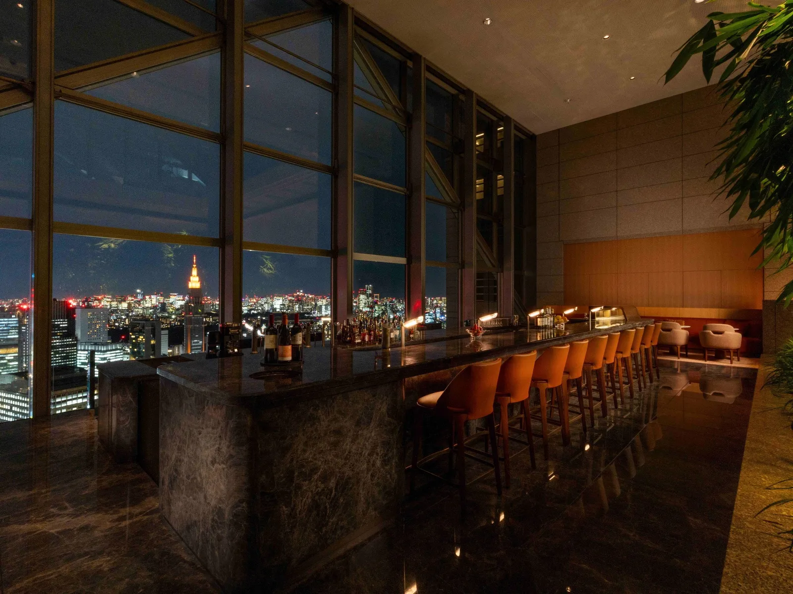 The Peak Bar at night: the stone counter with its stools and the window onto the city lights.