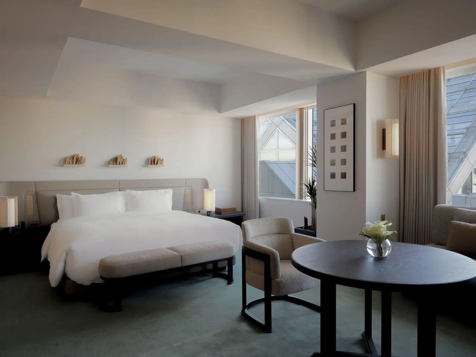 The 45 m² King room: the bed, the round table with 2 armchairs and the window onto the side of the tower.