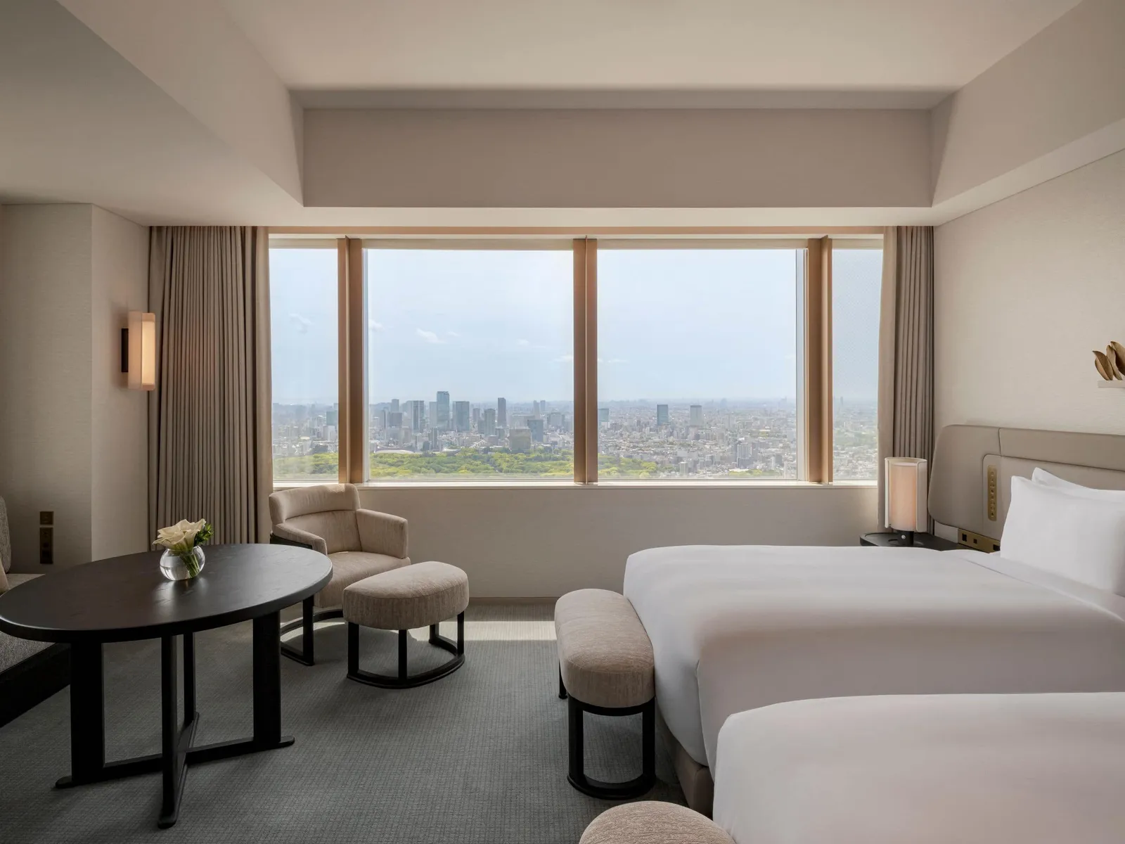 The Twin City View: 2 single beds, an oval table and a long window onto the city and the green of a park.