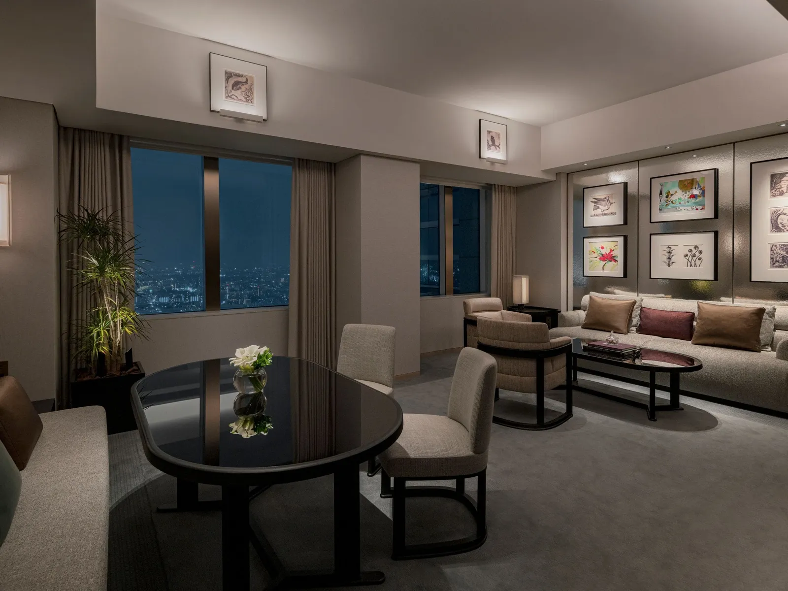 The Ambassador Suite at night: the dining table, the sofa under the pictures and the windows onto the city lights.