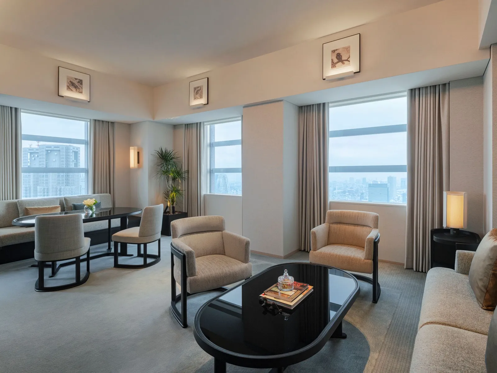 The Park Premier Suite living room: armchairs, a lacquered coffee table and the dining table in front of 3 windows.