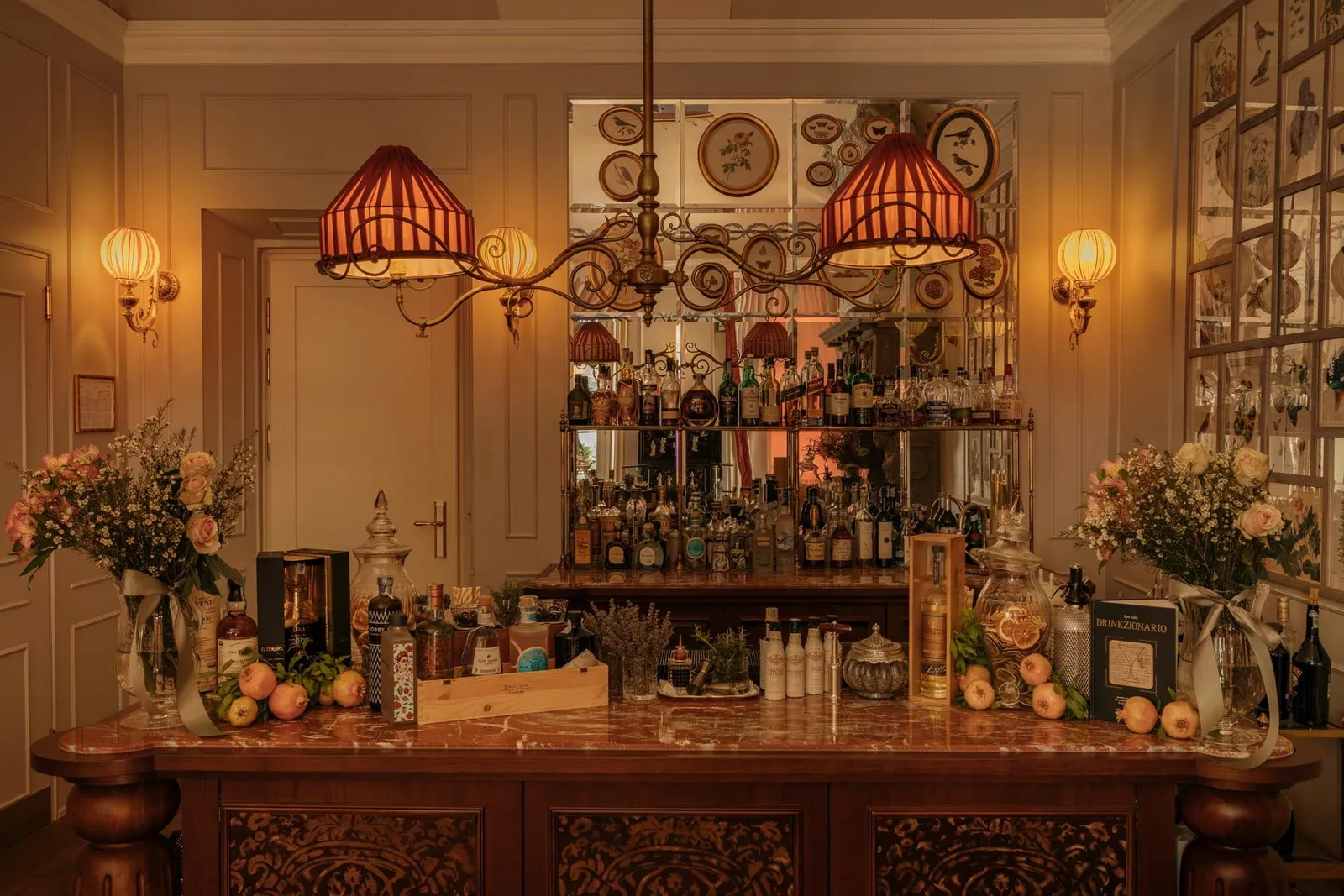 The bar counter with bottles, red lampshades and flowers
