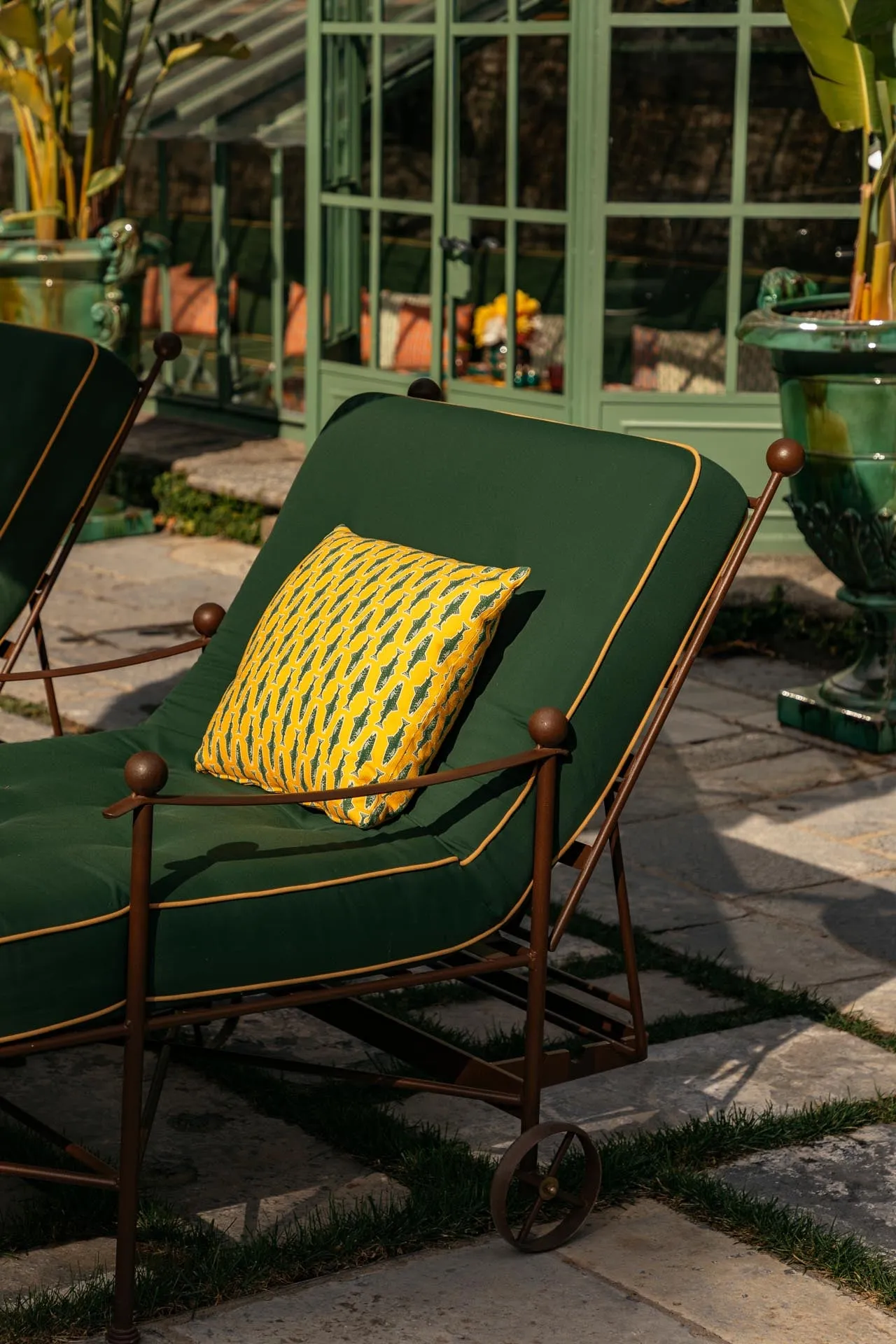 A green lounger with a yellow cushion beside the outdoor pool