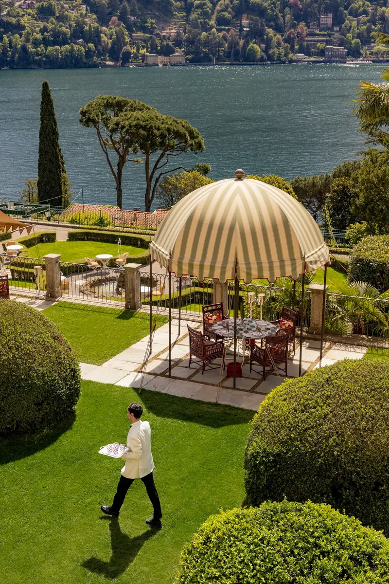 The restaurant terrace on the lawn, with a striped pavilion and the lake below